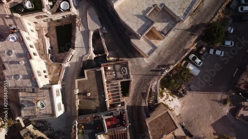 Man is standing on the balcony trying to catch the drone filming surroundings of Cappadocia. Aerial footage of Turkish old town and historical architecture. Travelling and tourism. Cultural heritage