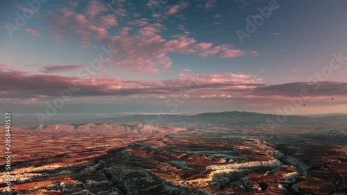 Stunning sunset bathes mysterious fairy chimney formations and rugged cliffs in vibrant colors. Dramatic aerial canyon views. Sunset over Cappadocia reveals striking terrain and colorful skies.