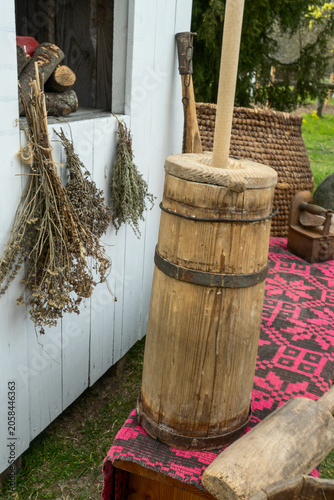 Authentic retro butter churner standing on a traditional red textile under soft daylight. Concept of cultural heritage and preservation of ancient traditions in modern simple lifestyle