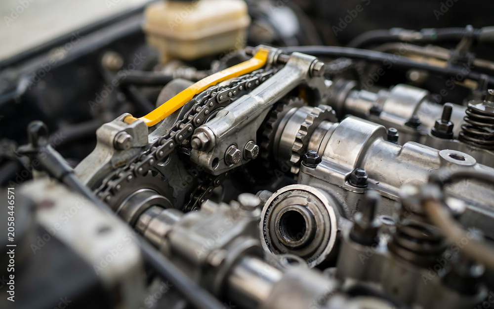 Fototapeta premium Close-up mechanic inspecting car engine components with wrench in garage workshop
