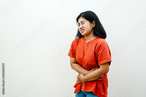 Foto Sick Asian woman holding stomach suffering from severe abdominal pain or menstru