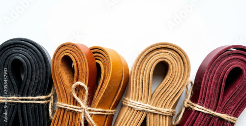 Colorful folded leather straps tied with twine on white background, craft material variety