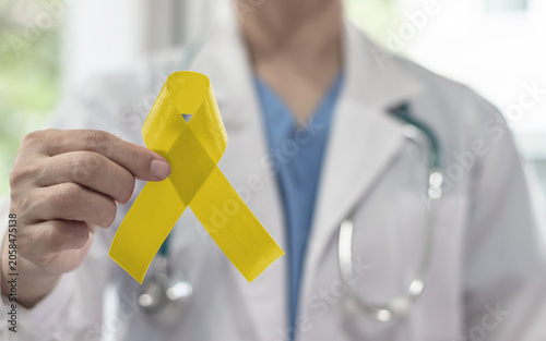 Yellow awareness ribbon for Sarcoma Bone cancer, Adenosarcoma, Bladder cancer, Liver disease, Spina Bifida Awareness Month and suicide prevention in doctor's hand
