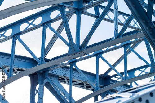 Fotografie Blue steel bridge structure with rivets, arches and industrial framework closeup