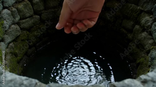 Hand Water Well Stone Moss Reflection Ripple Dark Stone Opening Human Hand Reaching Downward in Shadowed Nature Outdoors