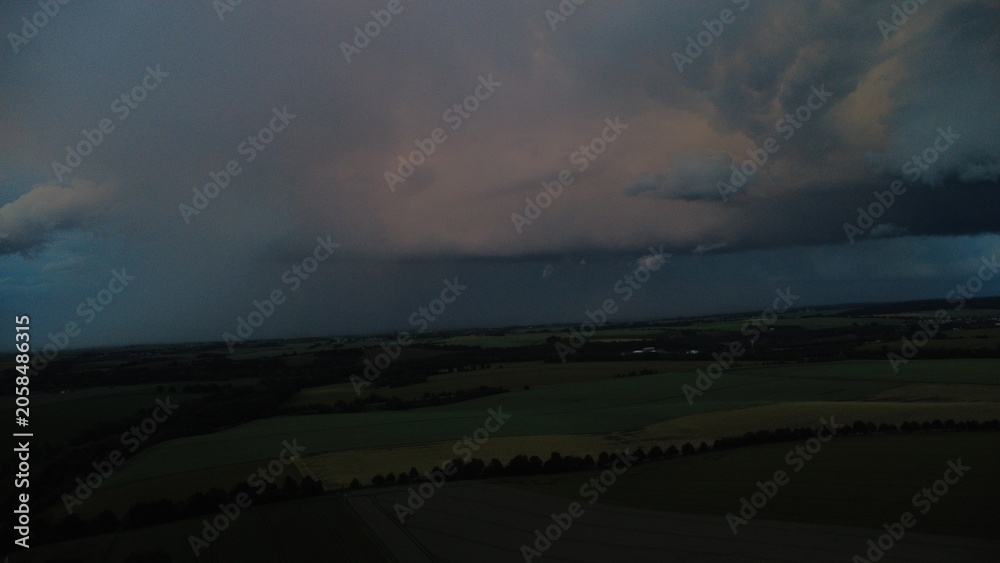 Obraz premium Aerial view of massive storm clouds spreading across the sky, capturing dramatic weather patterns and an impressive atmospheric landscape from above. The image highlights texture, scale, and the power