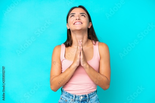 Obraz na płótnie Young caucasian woman isolated on blue background keeps palm together