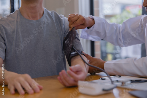 Doctor measuring blood pressure during a routine medical checkup in a healthcare clinic. Professional physician monitoring cardiovascular health, preventive care, diagnosis, and patient wellness.