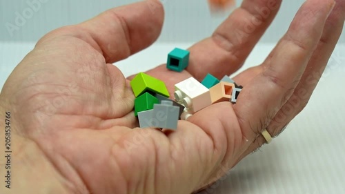 Various small, colorful toy building bricks falling into the open palm of a person's hand, isolated on a white background, representing collecting, hobby, nostalgia, and childhood memories