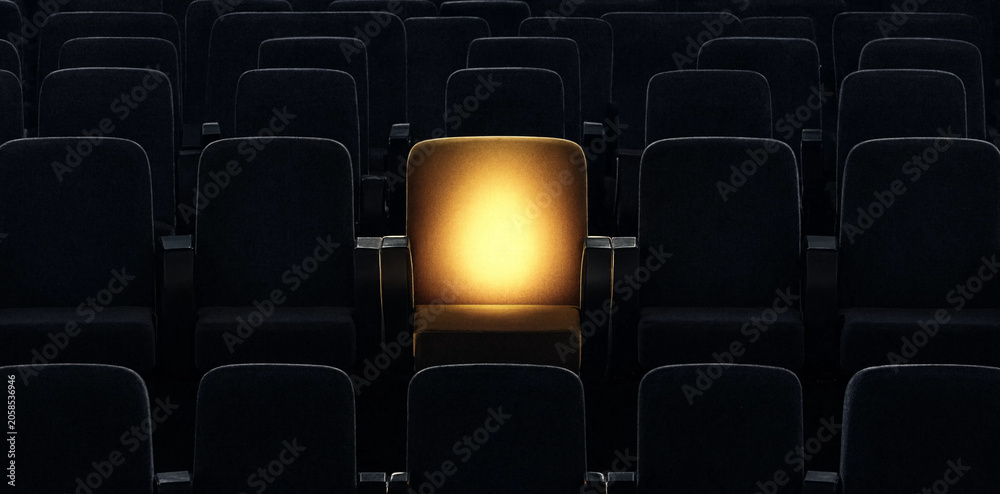 Fototapeta premium A single illuminated cinema chair glowing in a dark empty theater auditorium entertainment spotlight solitude performance interior abstract atmosphere presentation