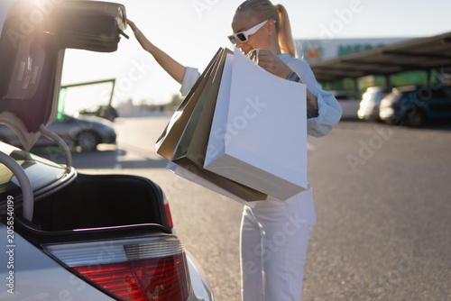 Canvas Print Young woman returning from shopping, smiling and loading purchased items in pape