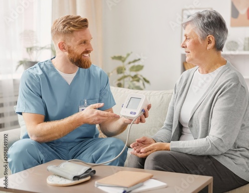 Nurse Explaining Home Blood Pressure Monitor to Senior Woman