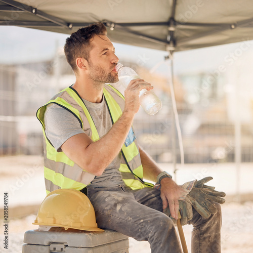 Construction worker drinking water in shade during heat