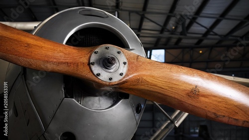 The wooden propeller of a vintage monoplane in a quiet hangar.