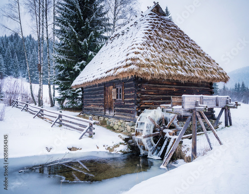 Old Slovak wooden water mill with a thatched roof from the old days in winter