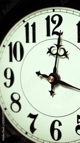 A vertical close-up shows a vintage analog clock face with black hands spinning rapidly as hours fly by. Concept of deadline pressure, urgency, lost time, and history passing.