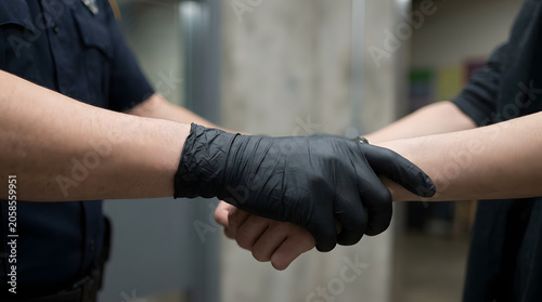 Police officer detaining suspect during arrest wearing black gloves