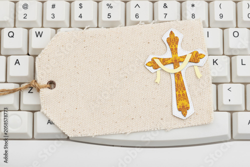 Fotografie Gold cross on a blank gift tag on white computer keyboard for weekly tithe