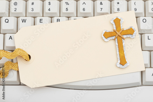 Fotografie Gold cross on a blank gift tag on white computer keyboard for weekly tithe