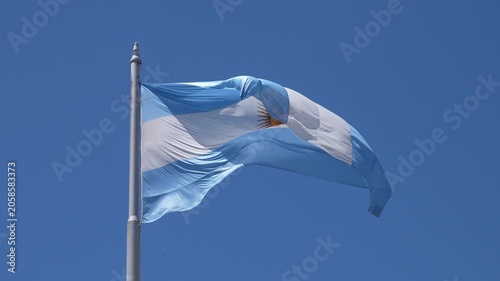 Argentine flag with the sun of may symbol slowly waving on a flagpole. National patriotism and pride concept against a clear blue sky