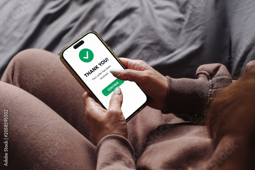 Foto Woman using smartphone to confirm online order at home