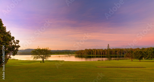 A peaceful wide landscape view of Lake Tinaroo in the Atherton Tablelands, Far North Queensland, captured during soft evening light with pastel pink, purple and golden tones across the sky. 