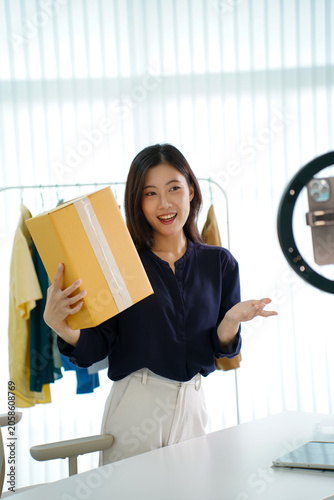 Asian woman live streaming online clothing sales with package at home studio
