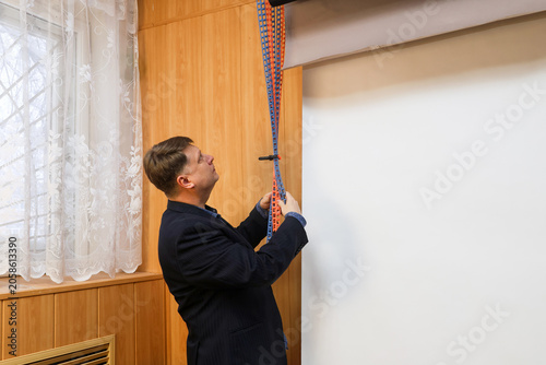 Bild auf Leinwand A male photographer lowers a white backdrop for a photo shoot in a professional studio