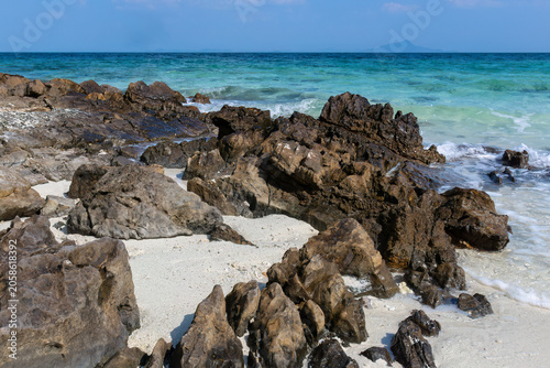 Rocky white sandy beach on the tropical island of Thale Waek, in the Andaman Sea near Krabi, southern Thailand. Turquoise green ocean in the background. 
