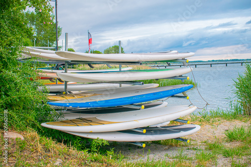 Foto Racks with SUP boards and surfboards stored outdoors on the riverbank or lake coast on a summer day