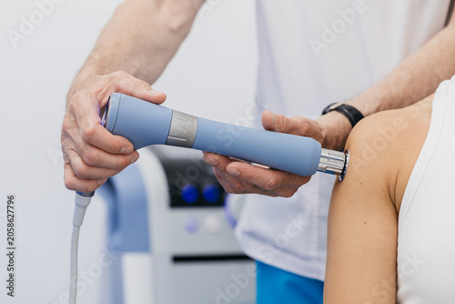 Fotografie Doctor administering shockwave therapy to a patients shoulder using a handheld d
