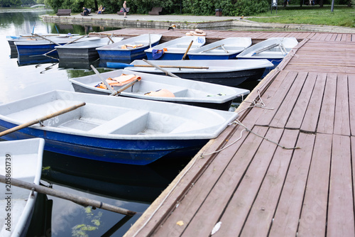Tableau sur toile Pleasure boats with orange life jackets parked at a wooden pier on the lake