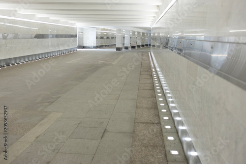Cuadro en lienzo Empty modern pedestrian underpass with marble walls and bright line lighting