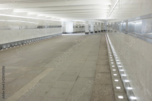 Foto Empty modern pedestrian underpass with marble walls and bright line lighting