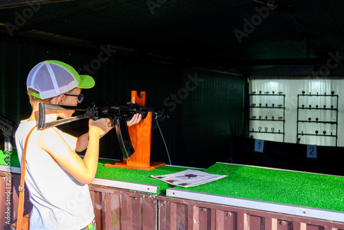 Obraz na plátně boy aims from an automatic rifle at black metal targets in the shooting gallery