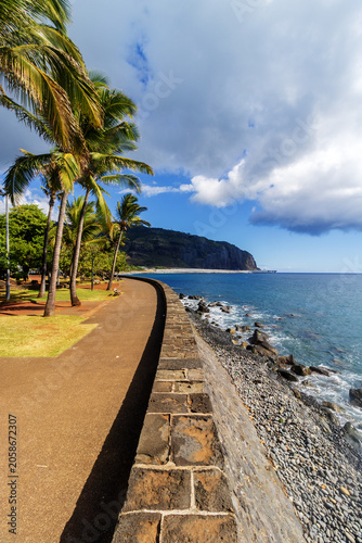 Coastal pathway with palm trees under tropical clouds - Barachois in Reunion island 