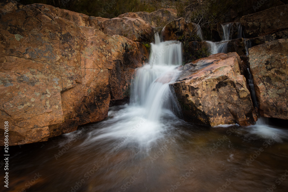 Obraz premium Cascading waterfall over red rock formations