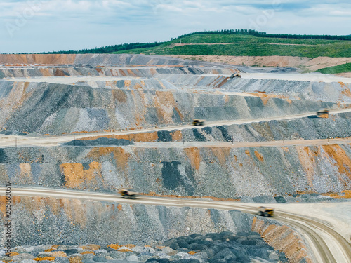 Fotografie Open pit mine haul trucks driving along winding mine terraces