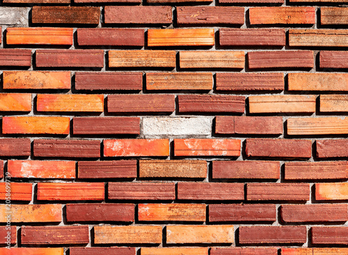 The old brown brick wall has loose bricks creating gaps. This wall is damaged from being exposed to sun and rain for a long period of time.