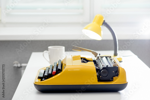 Writer desk with yellow vintage typewriter and coffee cup
