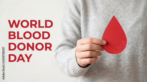 Person holding a paper red blood drop symbol for world blood donor day awareness campaign