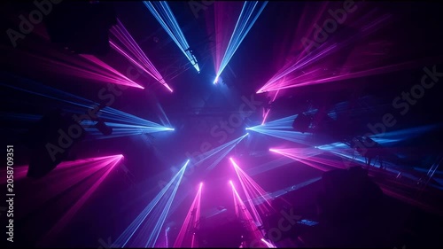 Vibrant laser beams illuminate a dark, atmospheric concert venue with purple and blue lights