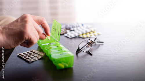 Middle aged caucasian man distributing scheduled dose of medication in dosette box