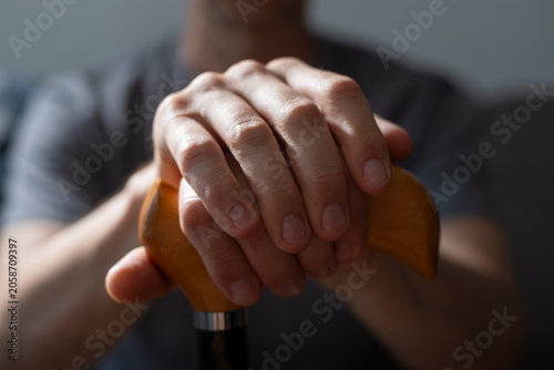 Middle age caucasian man hands holds cane closeup