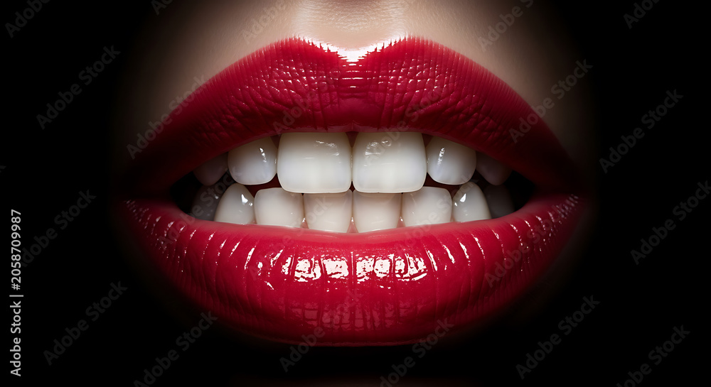 Fototapeta premium Close up shot of human female lips painted with vibrant glossy red makeup.