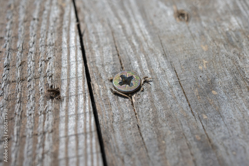 Close-up of weathered wooden boards with metal screw, rustic wood texture background, aged timber surface with cracks and natural grain pattern.