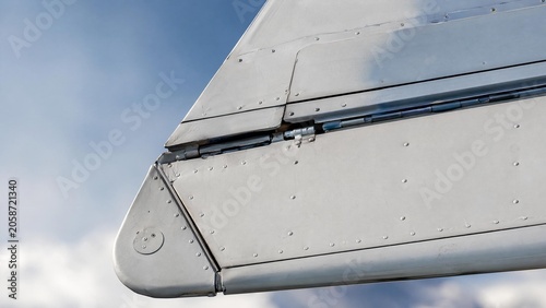Extreme close-up of a metal aircraft aileron with rivets and painted surface.
