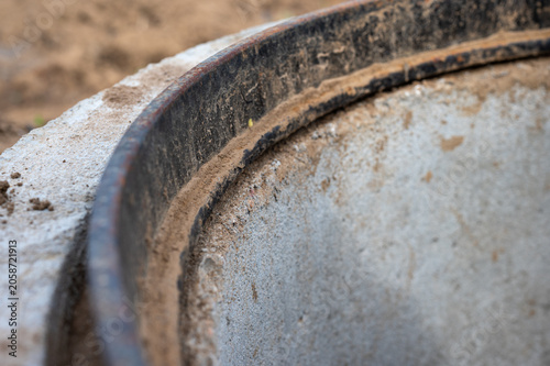 Close-Up of Concrete Manhole Ring with Rusted Metal Rim and Construction Dust, Industrial Infrastructure Detail.
