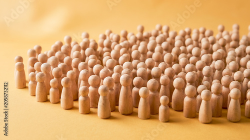 Foto Large crowd of blank wooden peg dolls gathers together closely on a warm yellow background, symbolizing unity, community, society, and population