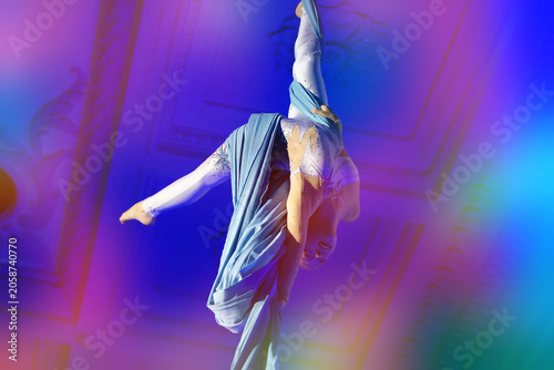 Dancer performs aerial silk routine at a theater during an evening event showcasing acrobatics and artistry
